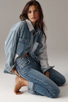 a woman is sitting on the ground with her hands in her pockets and looking at the camera