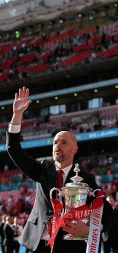 a man waves to the crowd as he holds up a trophy in front of him