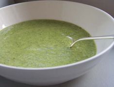 a white bowl filled with green soup on top of a table