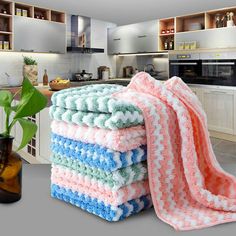 a stack of towels sitting on top of a kitchen counter next to a potted plant