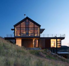 a large house on top of a hill with lots of windows and lights in it