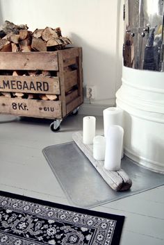 a pile of wood sitting on top of a floor next to a metal container filled with logs