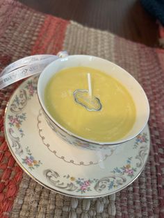 a bowl of soup is sitting on a saucer with a spoon and measuring tape