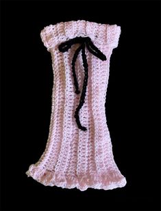 a pink crocheted bag with black ribbon on it's side, against a black background