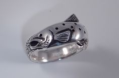 a fish shaped silver ring sitting on top of a table