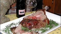 a large piece of meat sitting on top of a white plate next to a bottle of wine