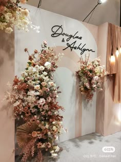 two tall vases filled with flowers sitting on top of a white floor next to a wall