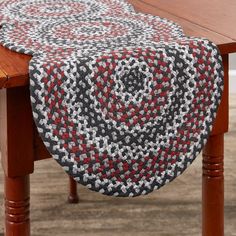 a table with a red, white and black crocheted runner on it next to a wooden table