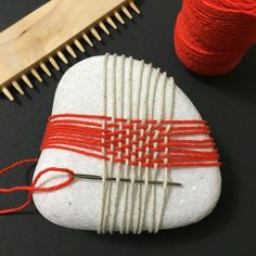 there is a rock that has been made with yarn on it and some knitting needles next to it