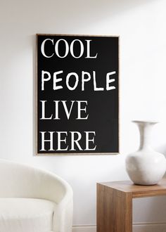 a black and white sign that says cool people live here on the wall next to a chair