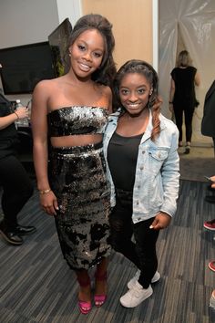 two young women standing next to each other in front of a crowd at an event