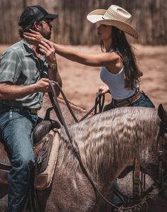 a man riding on the back of a brown horse next to a woman wearing a cowboy hat