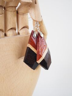 These unique earrings are made by layering a variety of wood species to create designs which highlight the beauty of the natural colors and grain patterns. They're shaped and faceted by hand, then finished with shellac for a durable shine. The hooks are made from 925 sterling silver. These earrings measure approximately 2.5 inches long and weigh a total of 9 grams. Brown Wooden Earrings As Gift, Unique Natural Wood Earrings, Brown Geometric Earrings As Gift, Brown Geometric Earrings Gift, Unique Brown Wooden Earrings, Handmade Brown Geometric Earrings, Artisan Brown Wooden Earrings, Artisan Brown Wood Earrings, Camano Island