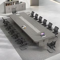 an empty conference table with black chairs and a phone on the desk in front of it