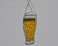 a beer glass hanging from a chain on a white wall with water droplets in it