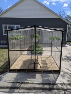 a caged in planter sitting on the side of a road next to a house