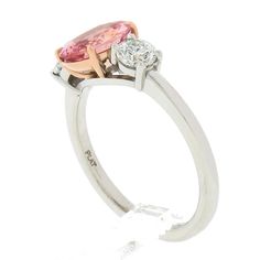 two tone gold and silver ring with an oval shaped pink stone surrounded by three round diamonds