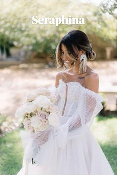 a woman in a white wedding dress holding a bouquet and wearing an off the shoulder gown