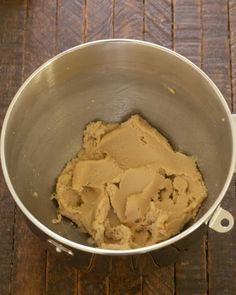 a metal bowl filled with peanut butter on top of a wooden table