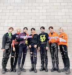 group of young men standing next to each other in front of a wall with graffiti on it