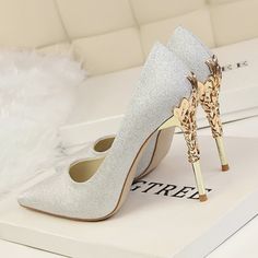 a pair of white high heels sitting on top of a table next to a box