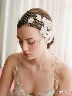 a woman wearing a veil and flowers on her head is sitting in a pink chair