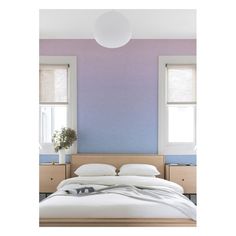 a white bed sitting under two windows next to a wall with purple and blue paint