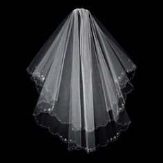 a white veil with beading on the bottom is hanging in front of a black background