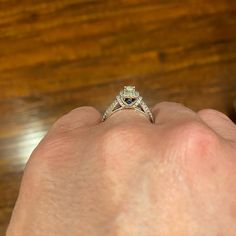 a person's hand holding an engagement ring with a heart shaped diamond on it