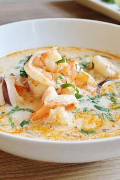 a white bowl filled with soup and garnished with shrimp