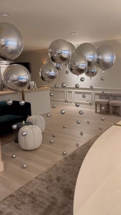 a living room filled with lots of silver balloons floating in the air next to furniture