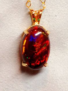 Big black fire opal 19x20mm 12ct.  Plenty of fire here and it has a bit of a diagonal pattern, good orange red fire surrounded by blue and amber and topped with more fire.  Melts in nicely with the yellow of the gold pendant mount, comes with a gold filled chain, your desired length. Fire Pendant, Opal Art, Fire Jewelry, Natural Opal Ring, Jewelry Opal, 14k Gold Engagement Ring, Fire Opal Necklace, Necklace Opal, Black Fire