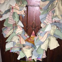 a close up of a wreath on a door with clothes hanging from the front and side