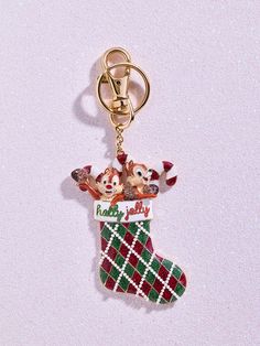 a christmas stocking keychain hanging from a metal hook on a white surface