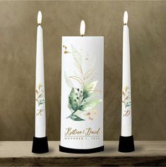 three candles are sitting next to each other on a table with leaves painted on them