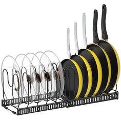 black and yellow kitchen utensils are hanging on a rack with white plates in it