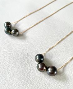 "An elegant black pearl necklace that is both simple and eye catching. Your choice of 1 or 3 genuine Tahitian black pearls \"float\" on a dainty 14k gold fill cable chain. Ideal to wear alone or for layering. Choose length of necklace in drop down menu. Pearls measures 9-10mm in diameter. The quality of the pearls reflects the pricing, these are A1 graded pearls. If you would like to know the exact necklace/pearls you would be getting, please let me know and I can send you a picture before shipp Classic Black Pearl Chain Necklace, Black Pearl Necklace With Round Bead Pendant, Black Pearl Necklace With Pearl Pendant, Black Tahitian Pearl Single Strand Jewelry, Black Tahitian Pearl Jewelry With Round Beads, Black Tahitian Pearl Round Beads Jewelry, Classic Black Pearl Drop Necklace, Minimalist Black Pearl Necklace With Pendant, Formal Black Tahitian Pearl Necklace