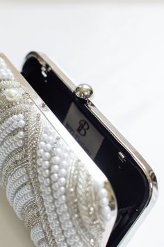 White Pearl Clutch Evening Bag designer made w/ Rhinestone Work Adorned with gorgeous silver bead & rhinestone work. This Aenor white evening clutch is accented with Pearl embellishments is a must-have in your wardrobe - a versatile accessory for any party outfit! Lining: Fabric Color: White & Silver Embroidery: Pearl & Rhinestones Size & Dimensions: Height - 5 inWidth - 8 inDepth - 1.5 in Fits most of the phones. Strap: Detachable shoulder metal chain strap Closure: Compartment button closure C White Evening Bag With Pearl Embroidery For Party, White Embellished Evening Bag For Party, Silver Evening Bag With Pearl Embroidery For Party, Silver Clutch With Pearl Embroidery For Party, White Clutch Evening Bag, Silver Pearl Embroidery Evening Bag For Party, Luxury White Clutch For Reception, Silver Party Evening Bag With Pearl Embroidery, Elegant Clutch With Pearl Handle For Reception