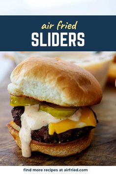 an air fried slider with cheese and pickles on it is sitting on a cutting board