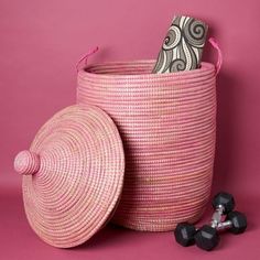 a pink basket sitting next to two black dumbs