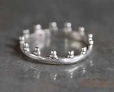 This dainty little crown ring is in fantastic pre loved condition, only very slightly oxidised by time. Roughly 16 mm inner diameter and according to the Wikipedia that makes it a US size 5 1/2, and a UK size K. Stamped inside 925 for sterling silver, quite light and comfortable to wear. For more vintage and antique rings: https://www.etsy.com/uk/shop/Meanglean?ref=seller-platform-mcnav&search_query=ring Back to shop: https://www.etsy.com/uk/shop/Meanglean?ref=si_shop Crown Rings, Vintage Tiara, Tiara Ring, Crown Ring, Oxidised Jewellery, Tiaras And Crowns, Antique Rings, Vintage Boho, Silver Band