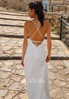 a woman in a white dress is standing on the stone walkway with her back to the camera