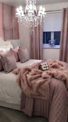 a bedroom with a bed, chandelier and pink pillows on the bed cover