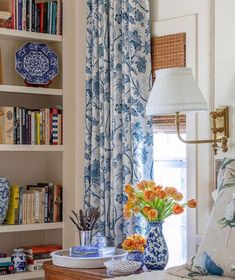 a bedroom with blue and white decor, bookshelves and vases on the bed