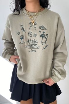 a woman wearing a sweater with drawings on it