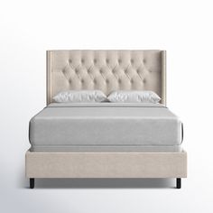 an upholstered bed with white linens and buttons on the headboard is shown