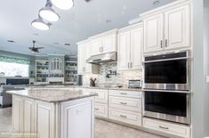 a large kitchen with white cabinets and marble counter tops, along with stainless steel appliances