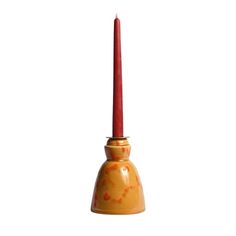 an orange candle holder with a red candle in it's center and a clock on the front