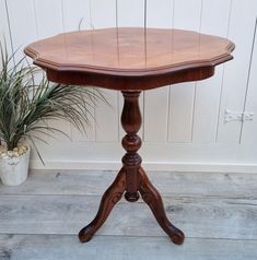 a small wooden table sitting next to a potted plant