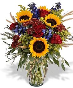 a bouquet of sunflowers and red roses in a clear glass vase with water